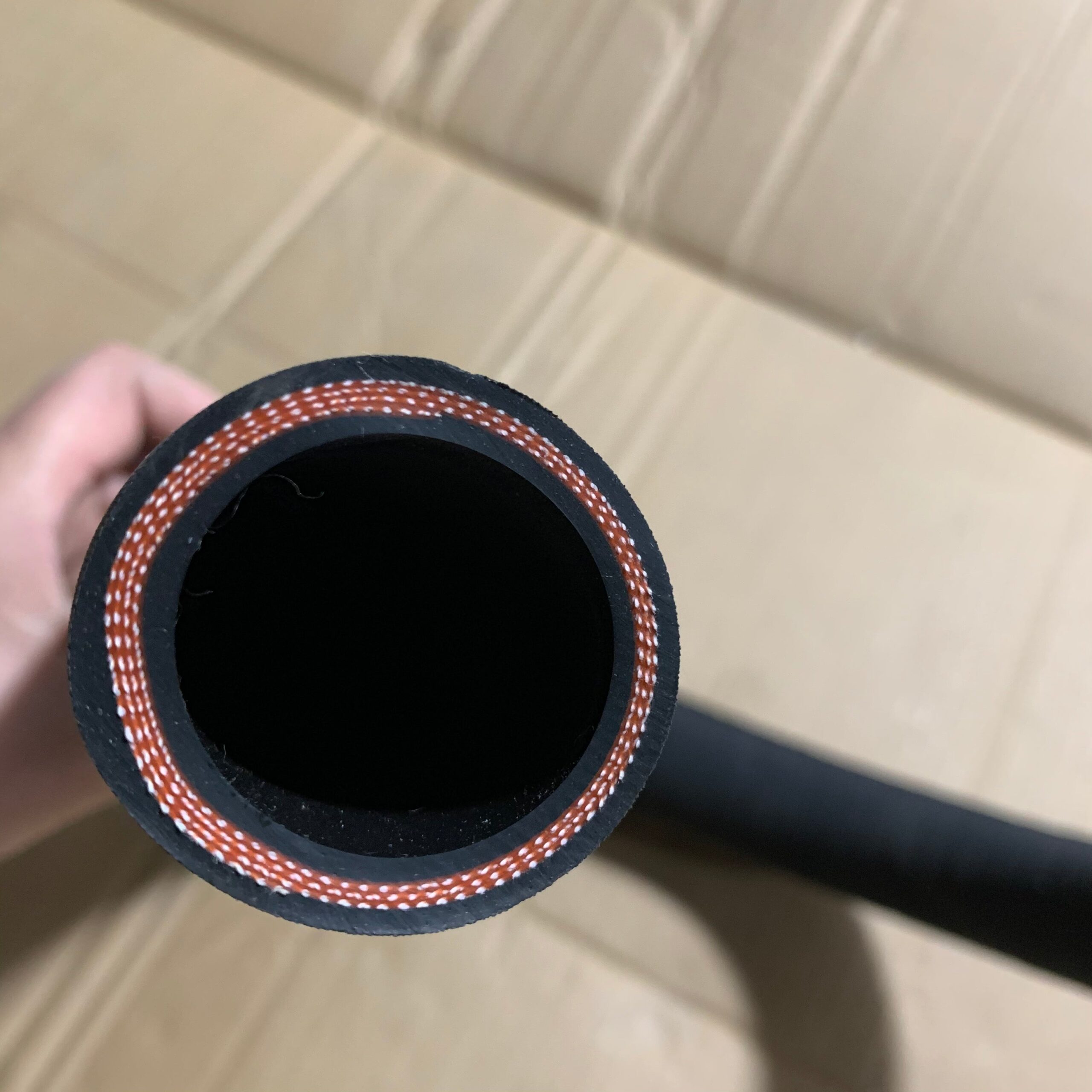 Black rubber hose end with braided outer trim and red-white thread stripe