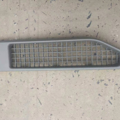 Gray air intake grille with rectangular mesh and mounting holes