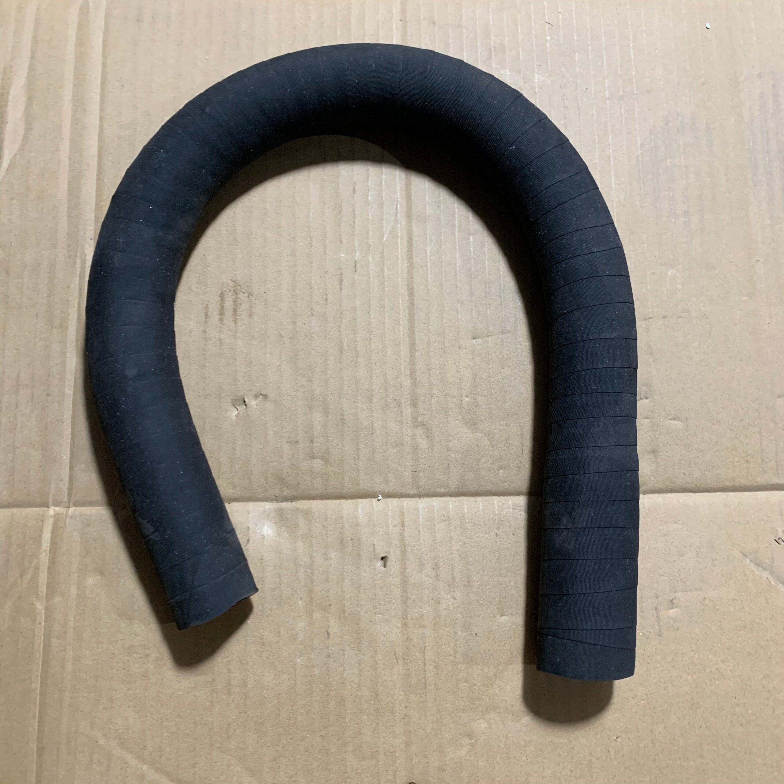Curved black rubber hose with thick walls and smooth reinforced bends