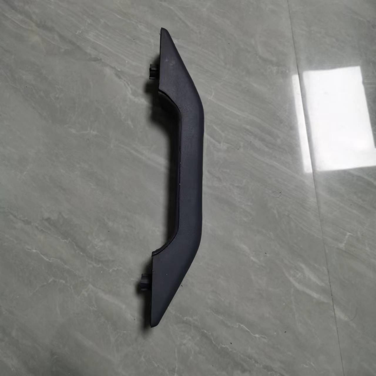 Front door inner armrest trim, dark plastic curved panel with mounting tabs