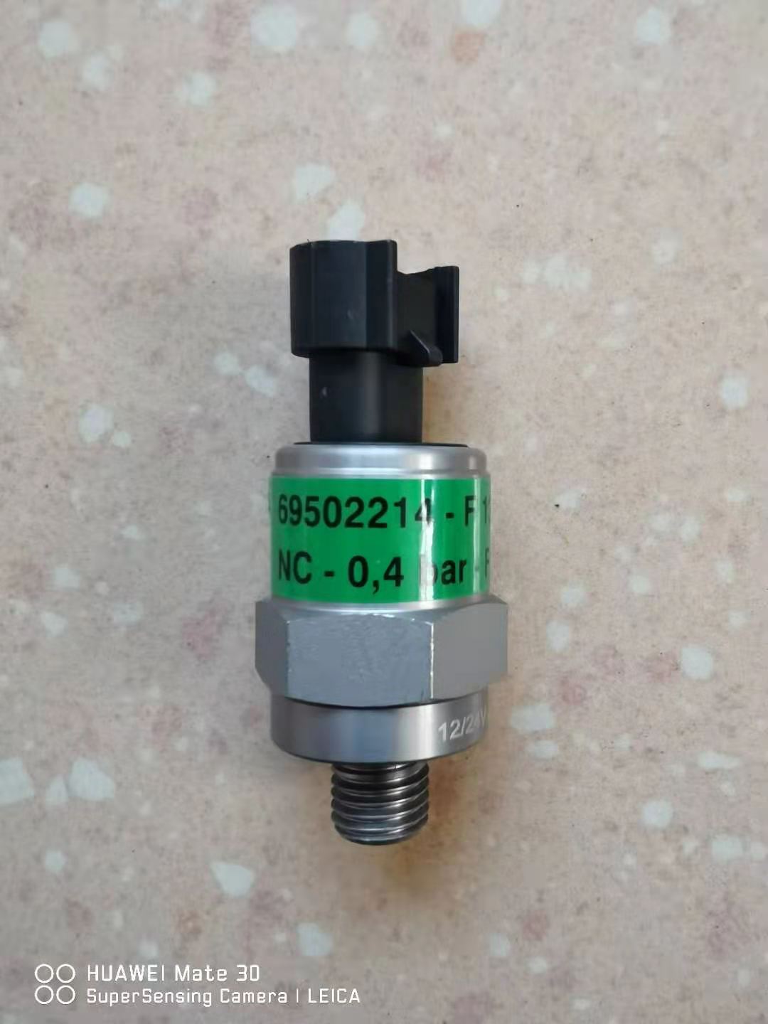 Water pressure sensor with green label, gray body, black connector, and threaded outlet