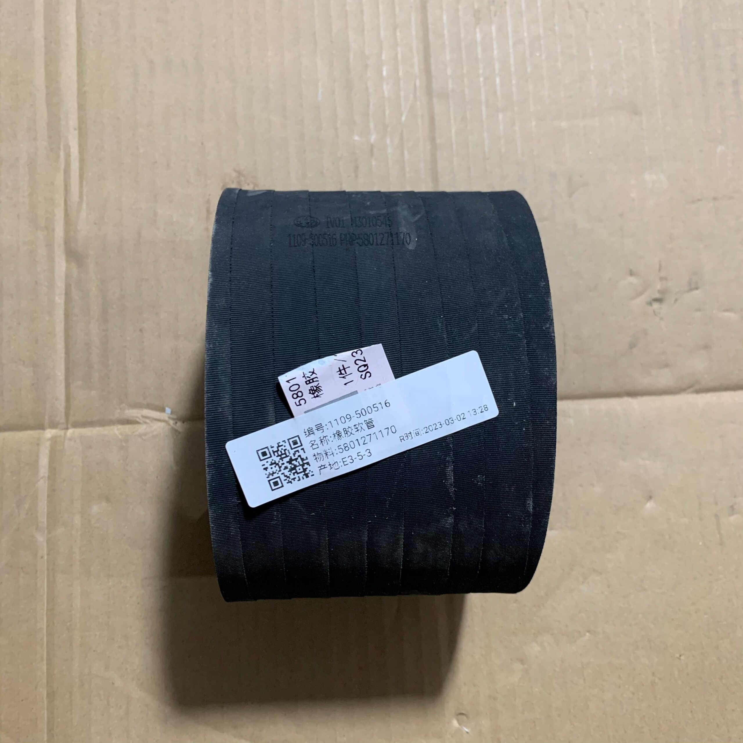 Short dark rubber truck hose section with paper label and textured surface